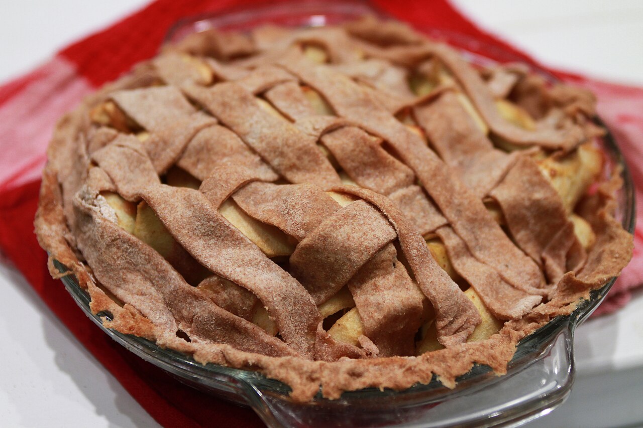 A golden double-crust apple pie, fresh from the oven and cooling on a rack.