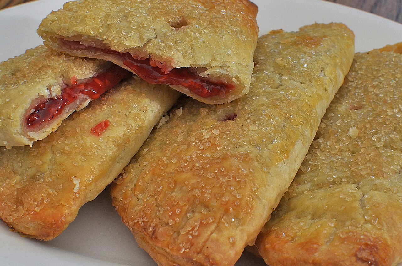 A batch of sugar-topped cherry hand pies, crimped and fresh from the oven.